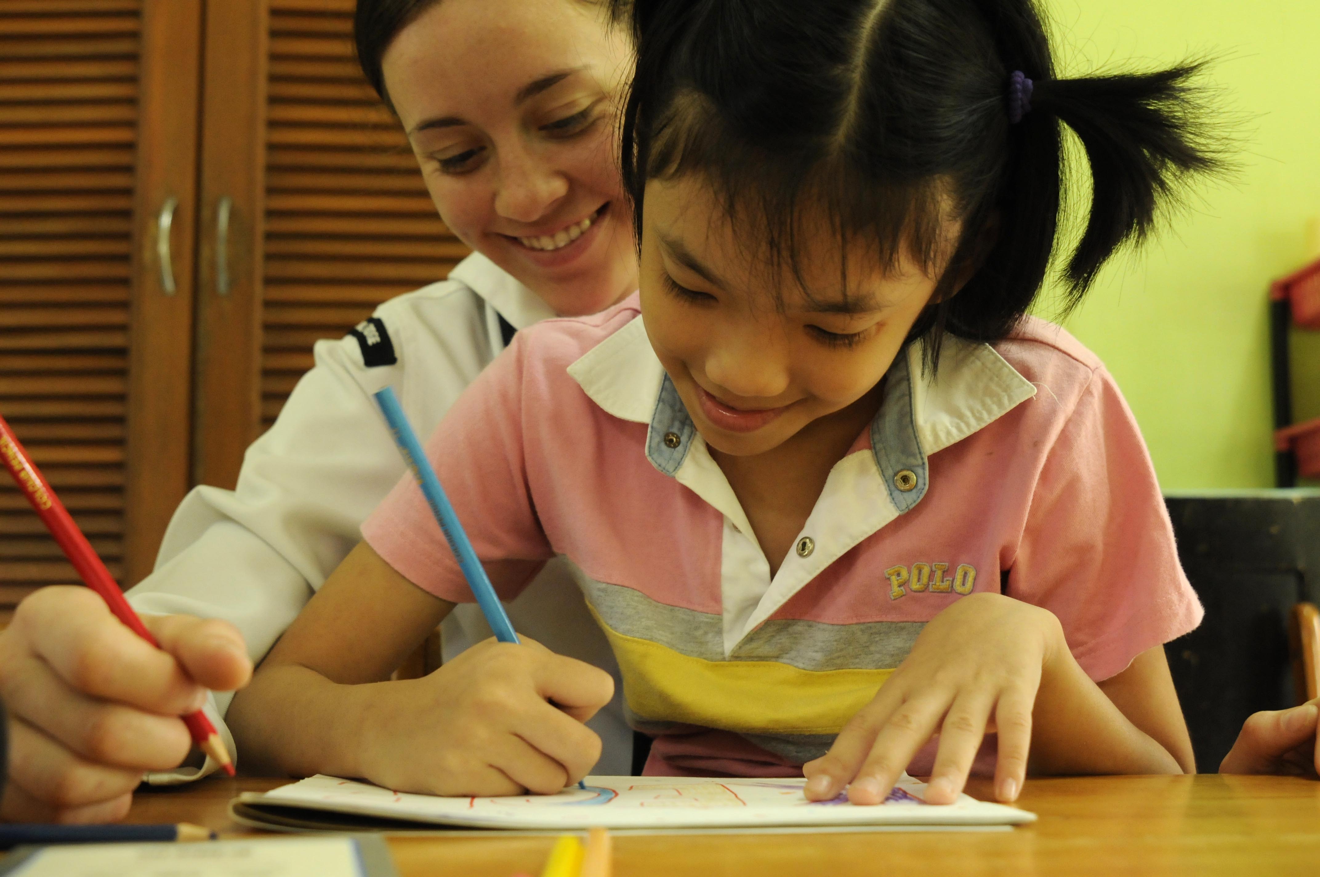 A woman helping a young girl with her homework.